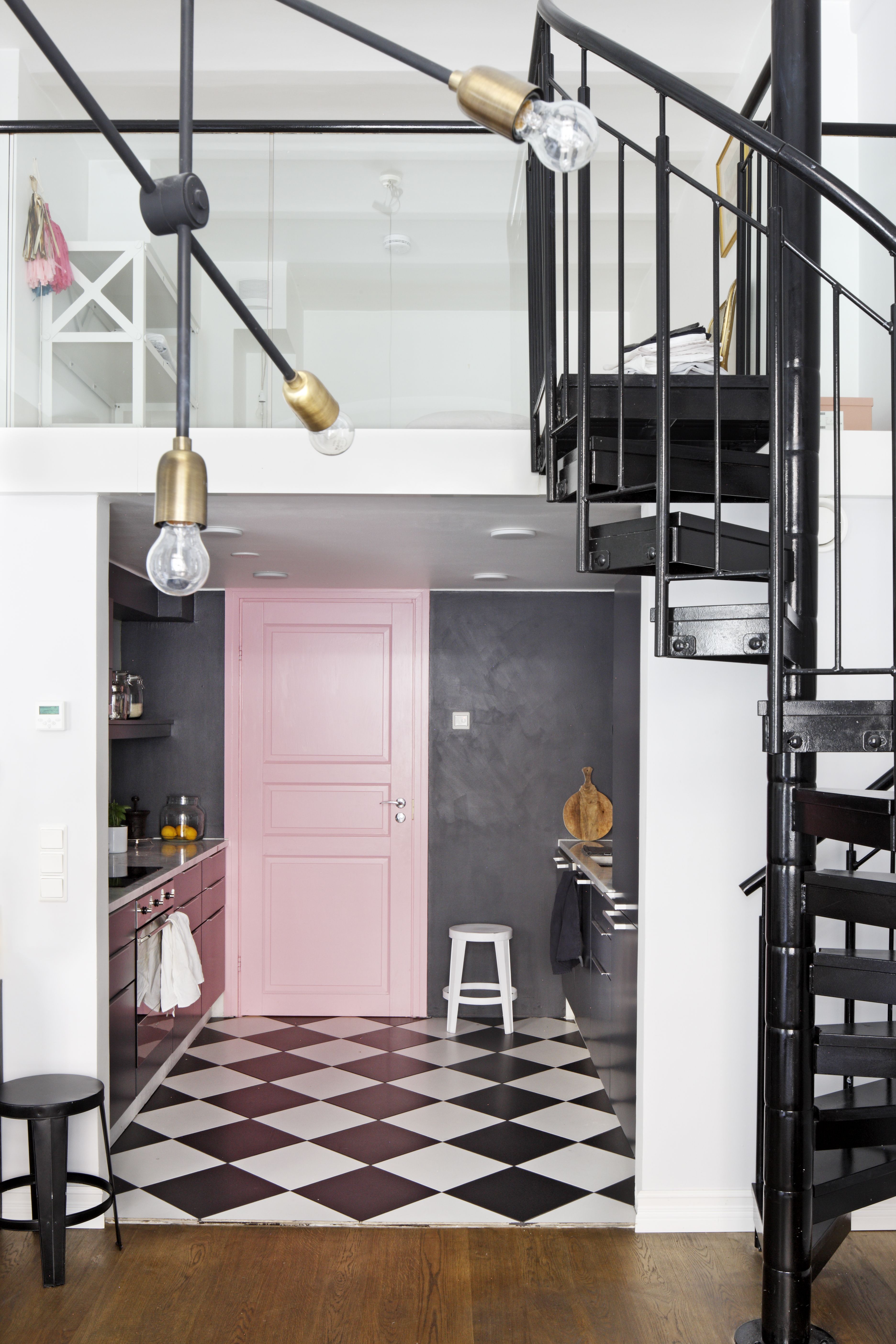 Parven alla sijaitsevaan keittiöön valittiin tumma väritys, jotta siitä tuli kodikas ja pesämäinen kontrastiksi muun tilan korkeudelle. Mustat kierreportaat johtavat makuuparvelle.