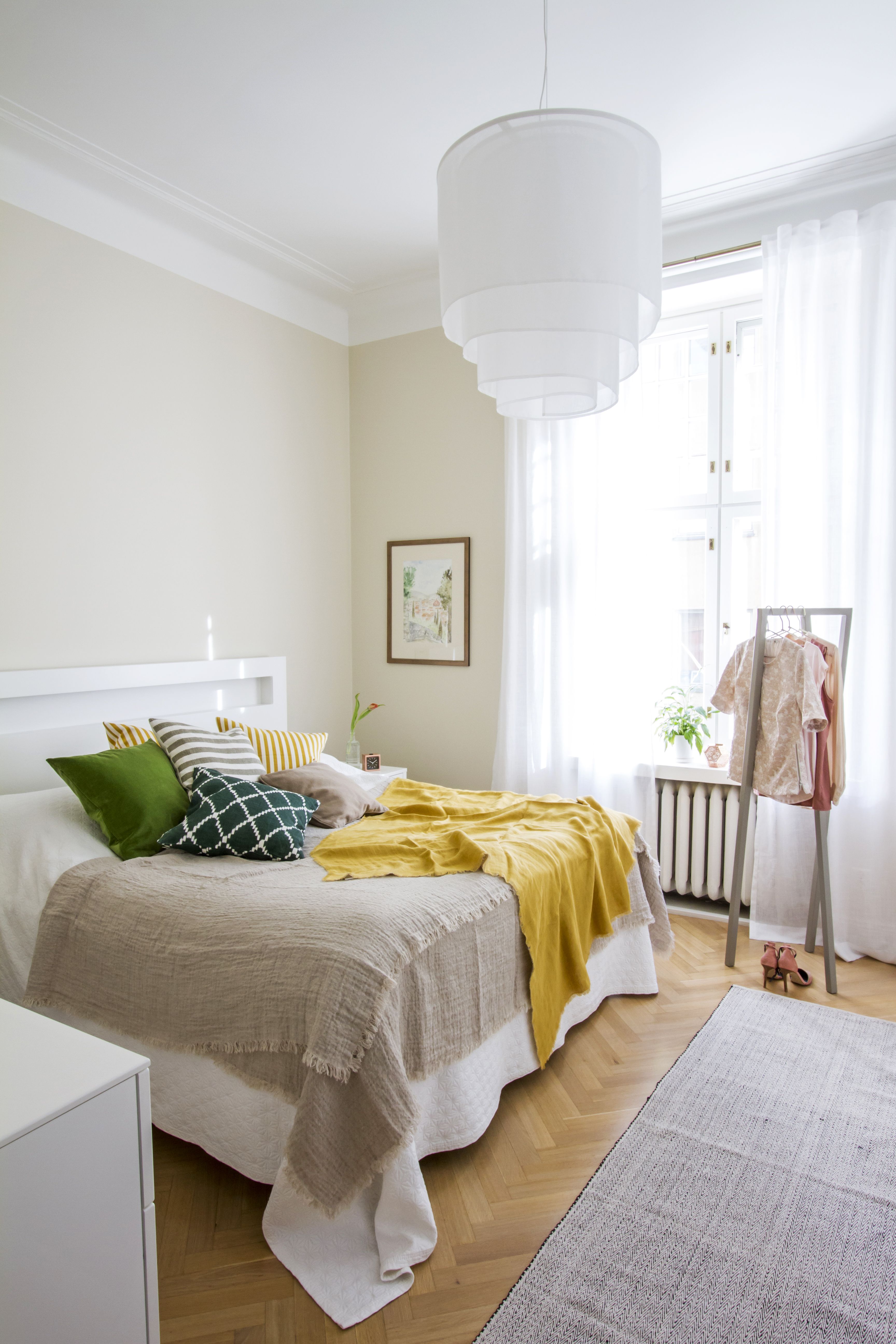 Makuuhuoneen värimaailma on poimittu seinälle ripustetusta akvarellista. Seinät maalattiin himmeällä Tikkurilan Symphonyn Tofu-sävyllä. Hiekan värinen pellavainen päiväpeitto, keltainen shaali, samettityynyt ja ikat-kuvioinen tyyny ovat Mokosta, Hayn vaateteline henkareineen on Formverkista sekä vaatteet ja matto Dotsista.