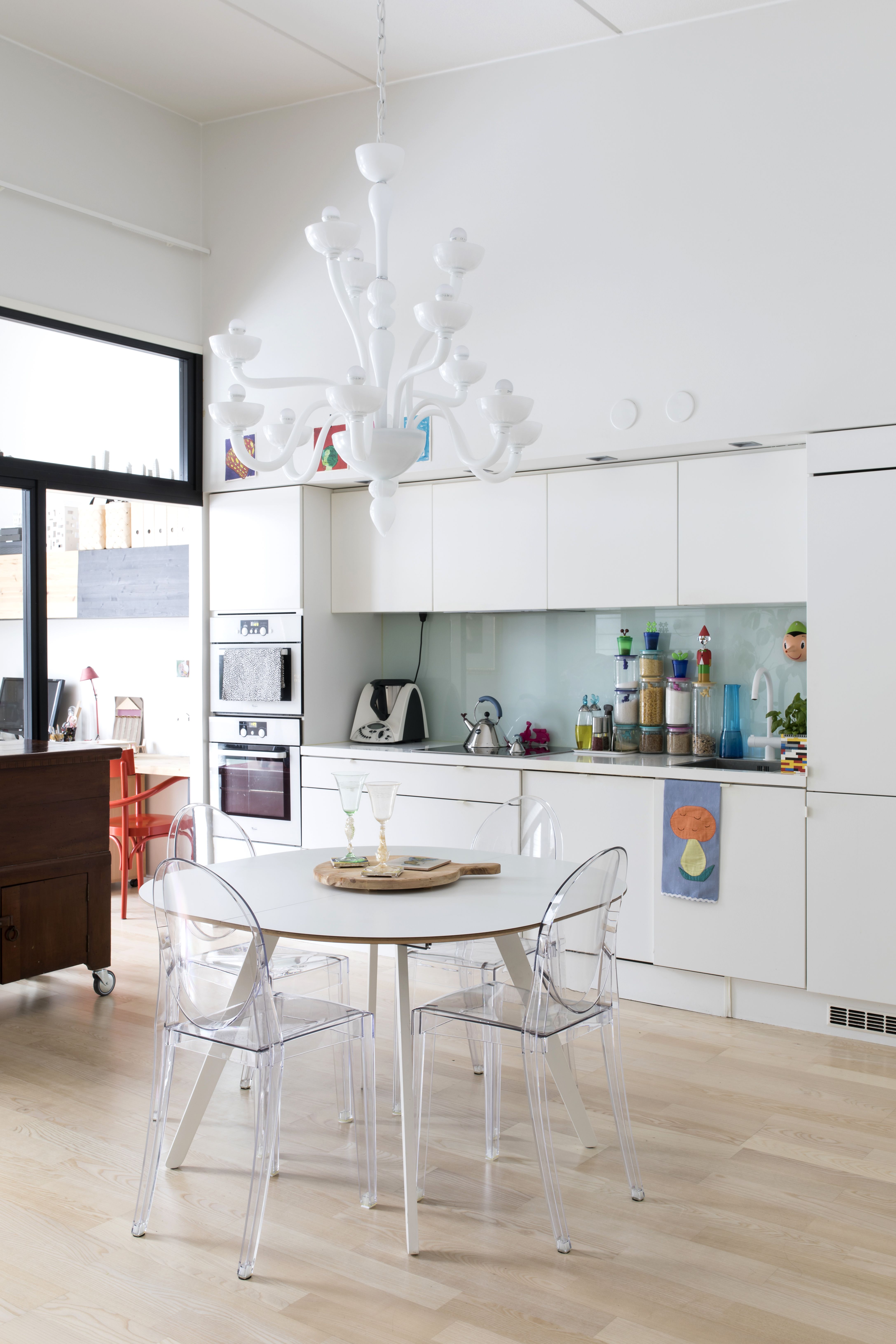 Korkealla oleva katto saa huoneen tuntumaan suuremmalta. Pyöreä pöytä ei vie liikaa tilaa, ja sen äärelle mahtuu monta ruokailijaa. Kartellin Ghost-tuolit Marzia ja Arto toivat Italiasta. Kattovalaisin on tilattu Marzian ystävän Bagliori di Murano -kaupasta. Se on tehty käsin Muranossa. Keittiön vieressä on lasiseinällä erotettu työhuone.