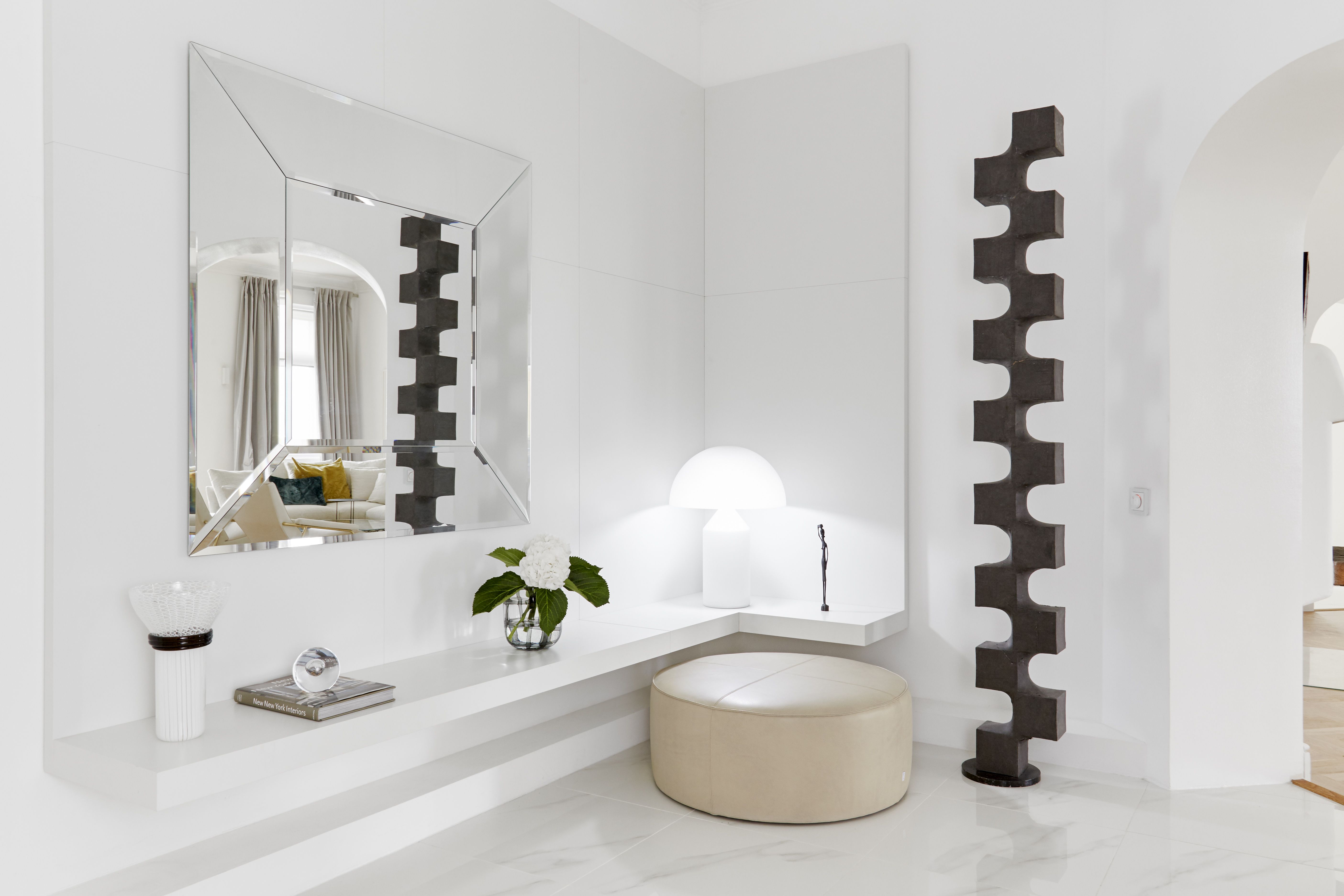 Eteinen koki täydellisen muutoksen ja on nyt iso ja valoisa. Casamilanon peili on kiinnitetty Brasserie-moduuli, jonka hyllyn alla naamioituna koteloon ovat uudet putkivedot. Lattian kiiltävä, kevyesti kuvioitu Laattapisteen kuivapuristelaatta on samaa kuin keittiössä ja kylpyhuoneessa. Pyöreä nahkarahi on Moltenin Domino, maljakko Veninin. Atollo-valaisimen on suunnitellut Vico Magistretti. Korkea tilatyö on taiteilija Harri Leppäsen.