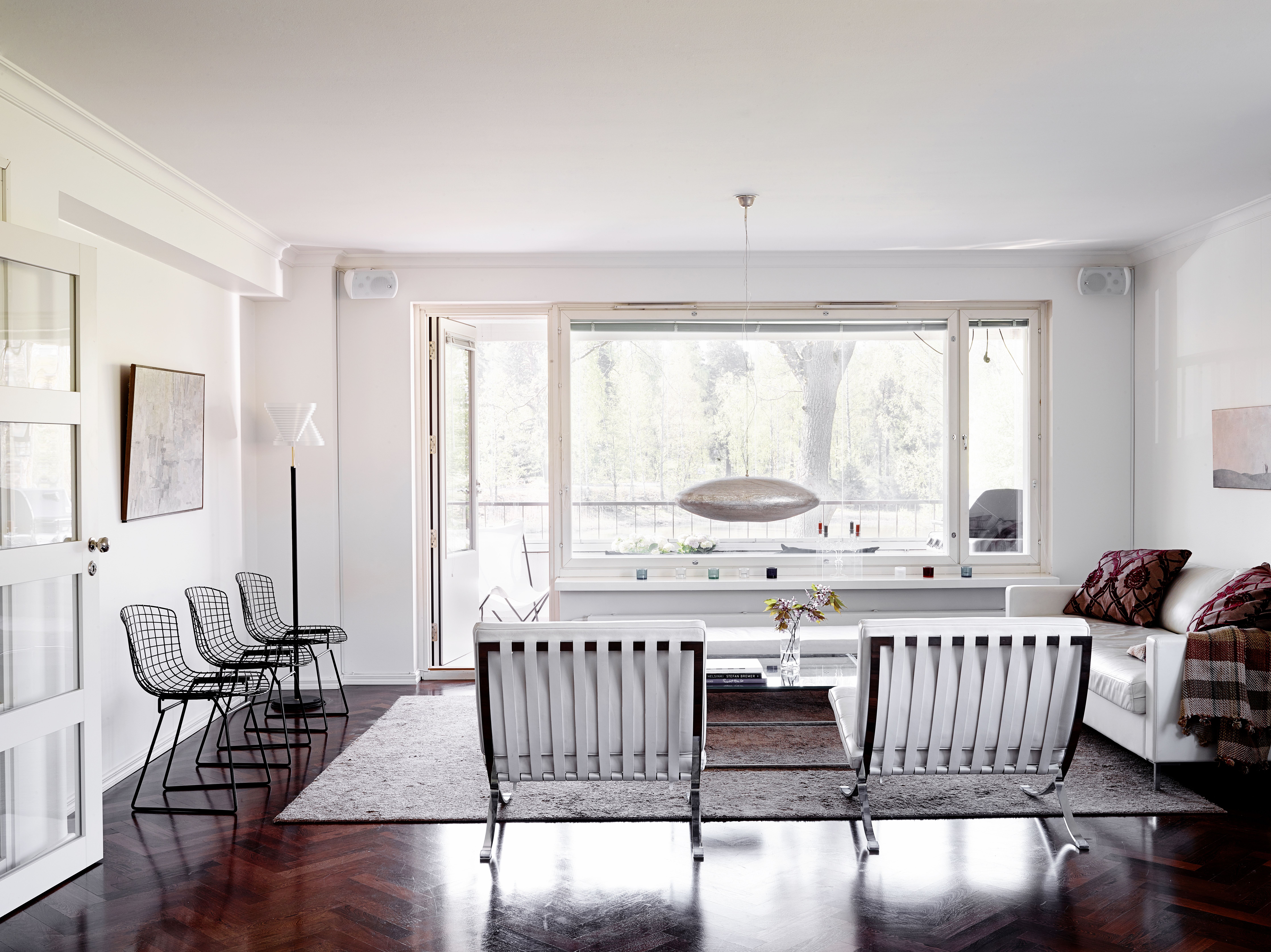 Olohuoneen päädyssä on parveke, jolta voi ihailla vihreyttä ja merenpoukamaa. Käsintehty messinkivalaisin on espoolaisesta Home Bazaar -sisustusliikkeestä. Mies van der Rohen Barcelona-tuolit olivat pitkäaikainen haave, joihin säästettiin.