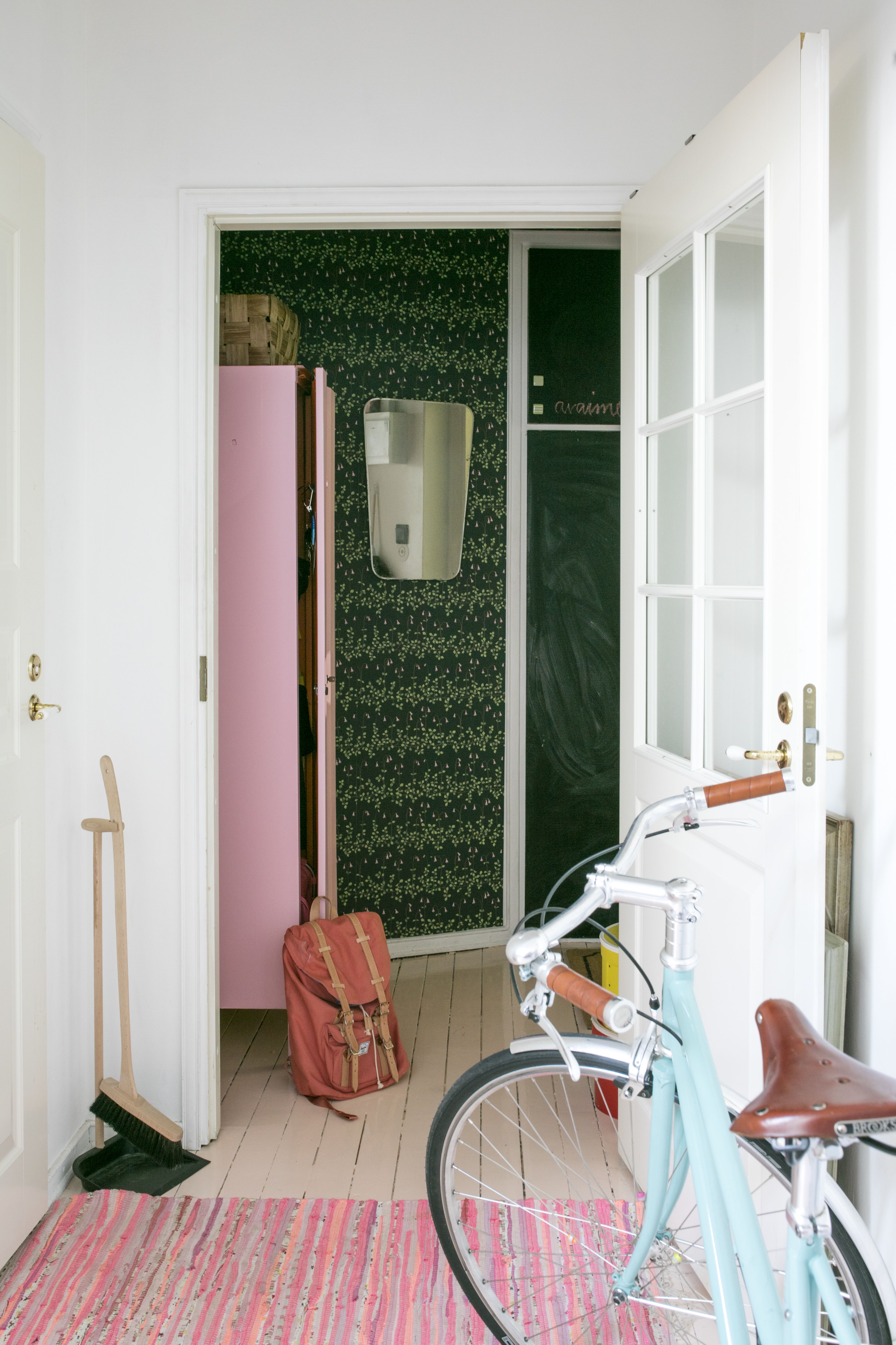 Eteinen on ainoa huone, jossa on tumma värimaailma. Sandbergin Linnea-tapetissa kukkivat vaaleanpunaiset vanamot. Vanha työmaakaappi löytyi Lahtelaisesta kirpputori Kisällistä. Pelagon kaunista Capri-pyörää Iina ei raaski piilottaa kellariin.