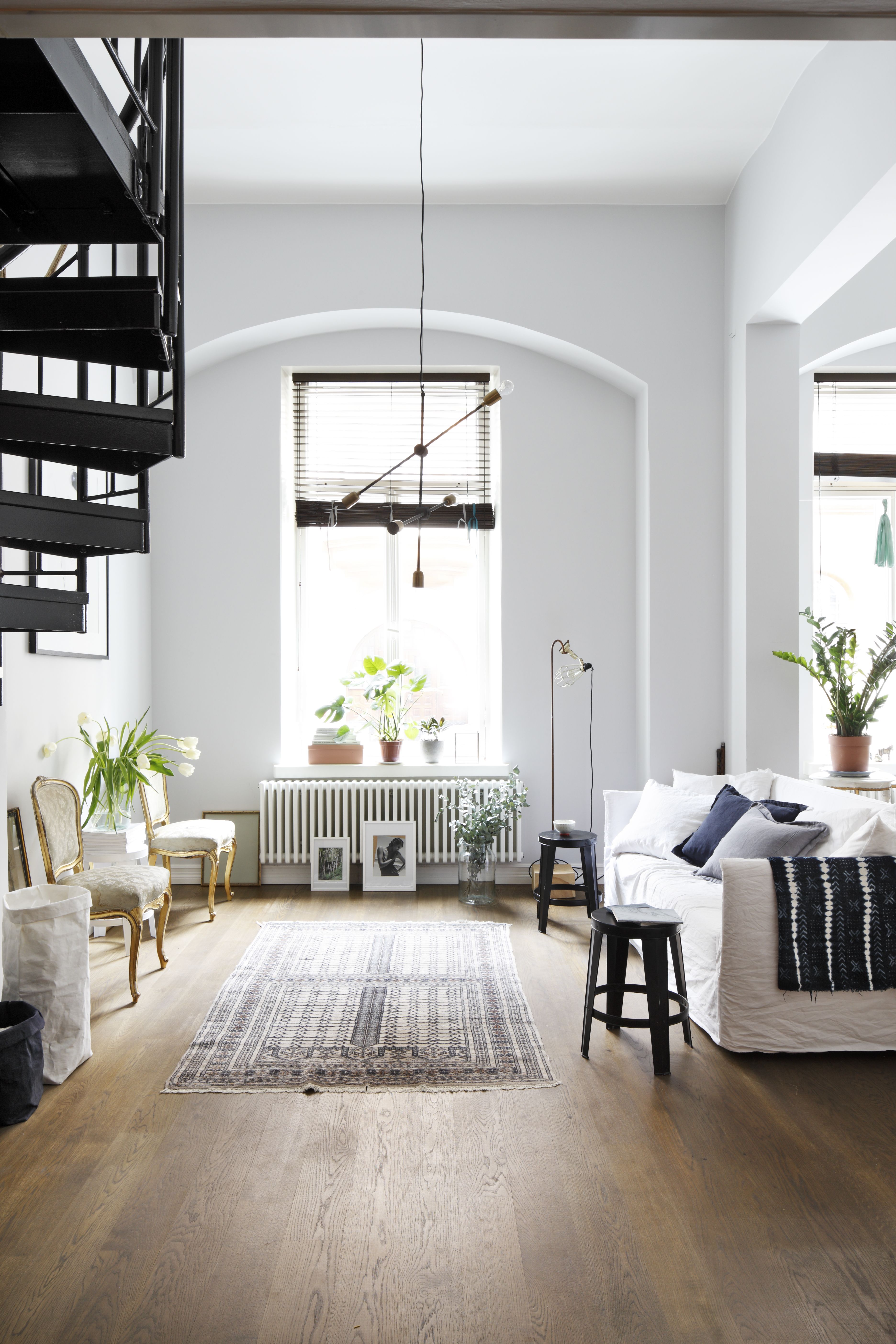 Gervasonin Ghost-sohva jakaa alakerran tilan oleskeluun ja ruokailuun. Olohuoneen keskipiste ei ole tv vaan perityt vanhat tuolit. Portaiden väriksi valittiin musta, jotta valkoiseen tilaan syntyisi jännitettä. Kattovalaisin on House Doctorin.