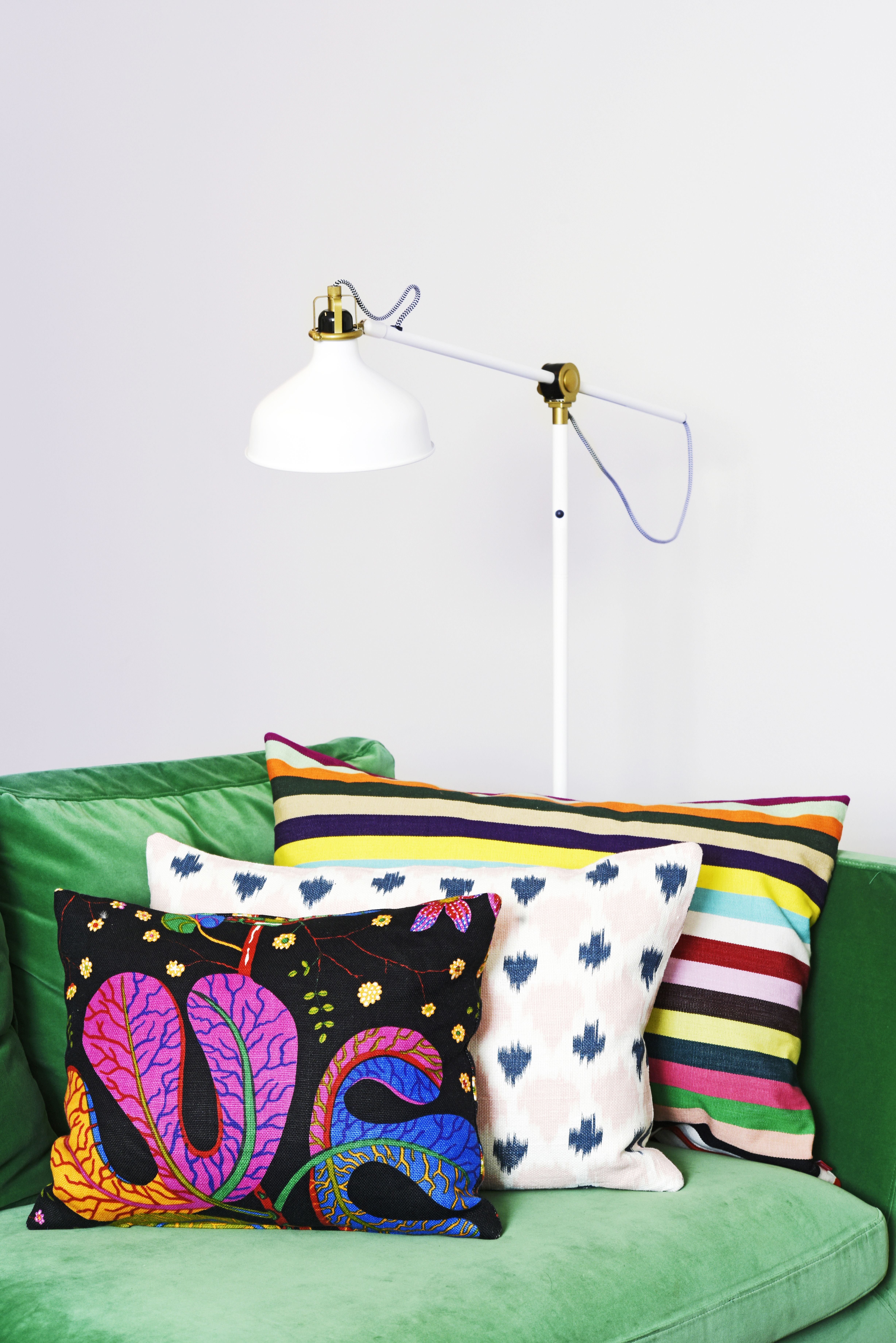 Ikean vihreä samettisohva sai kaverikseen Svenskt Tennin mustapohjaisen tyynyn, hempeän vaaleanpunaisen pellavatyynyn Moko Marketista ja reipasta raitaa Ikeasta.