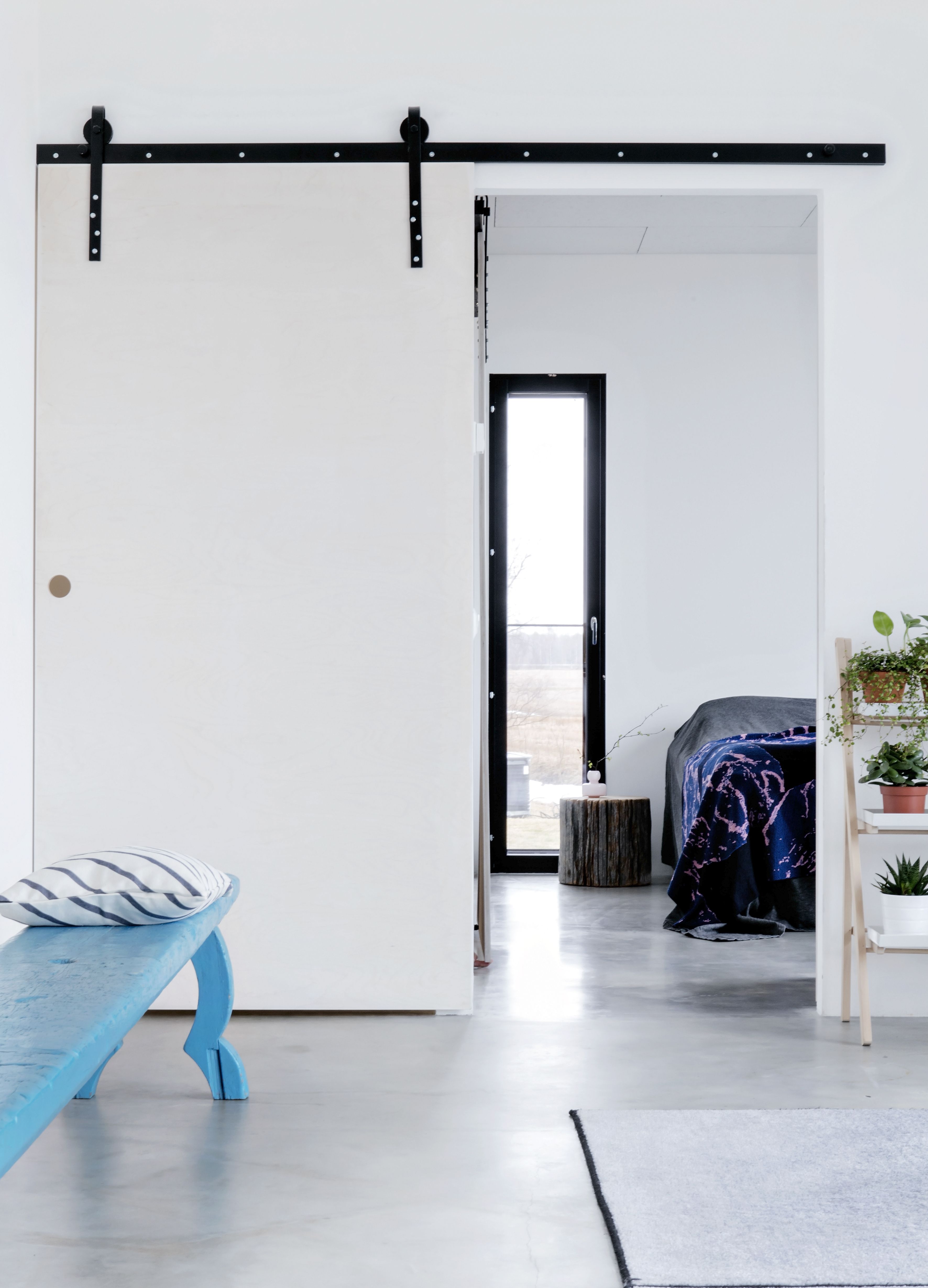 Olohuoneen lattia on betonia, jonka päälle laitettiin likaa hylkivä Mastertop 100 -pinnoite. Turkoosi penkki on samasta vanhasta hirsitalosta kuin ruokapöytä.