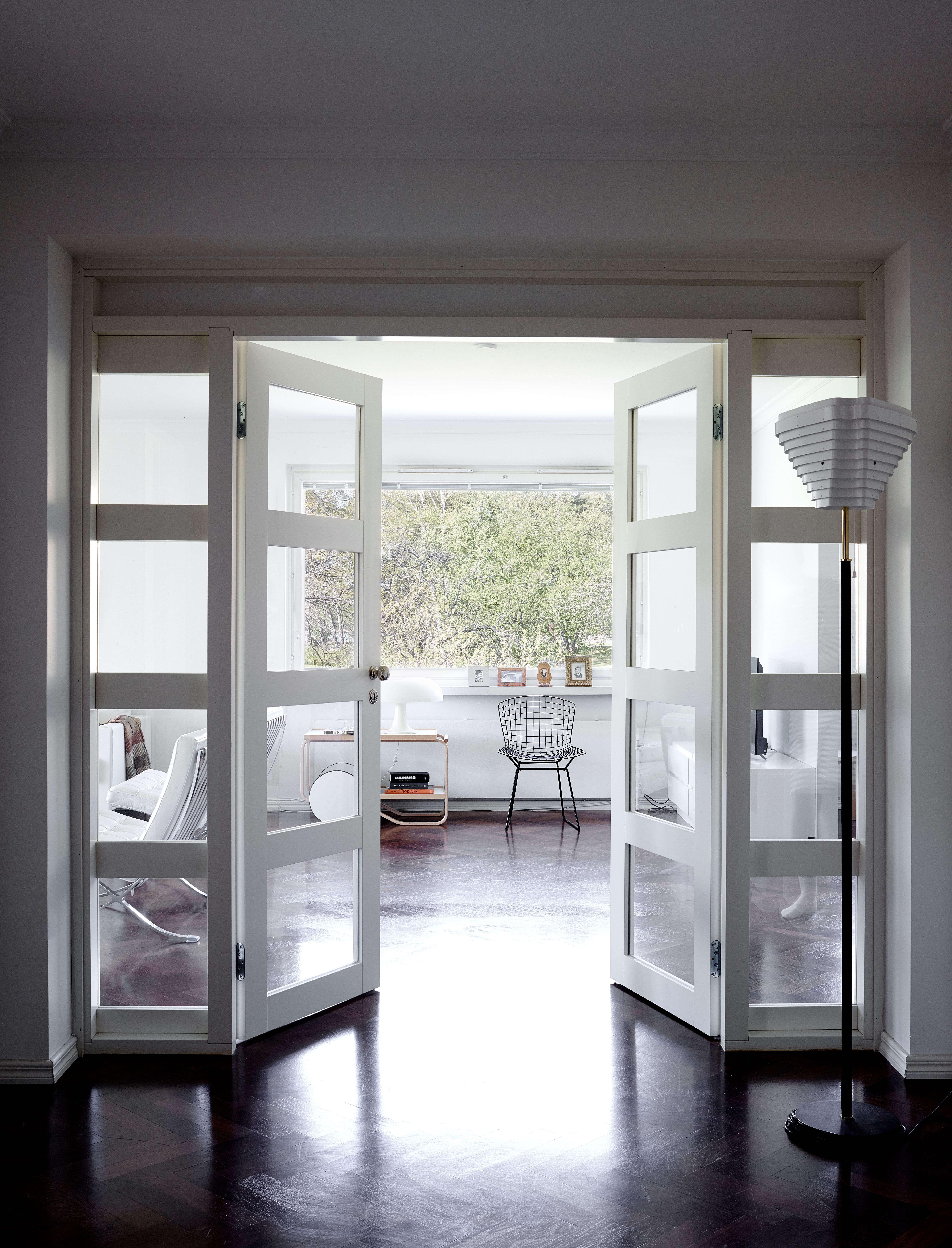 Eteishallin pariovet aukeavat olohuoneeseen, joka on samaa tilaa ruokailuhuoneen kanssa. Alvar Aallon suunnittelema jalkalamppu istuu hillittyyn tyyliin. Pikkuparlamentin vanhat terassituolit ovat Bertoian ja päätyivät kotiin, kun ravintola aikoinaan lopetti ja myi irtaimistonsa. 