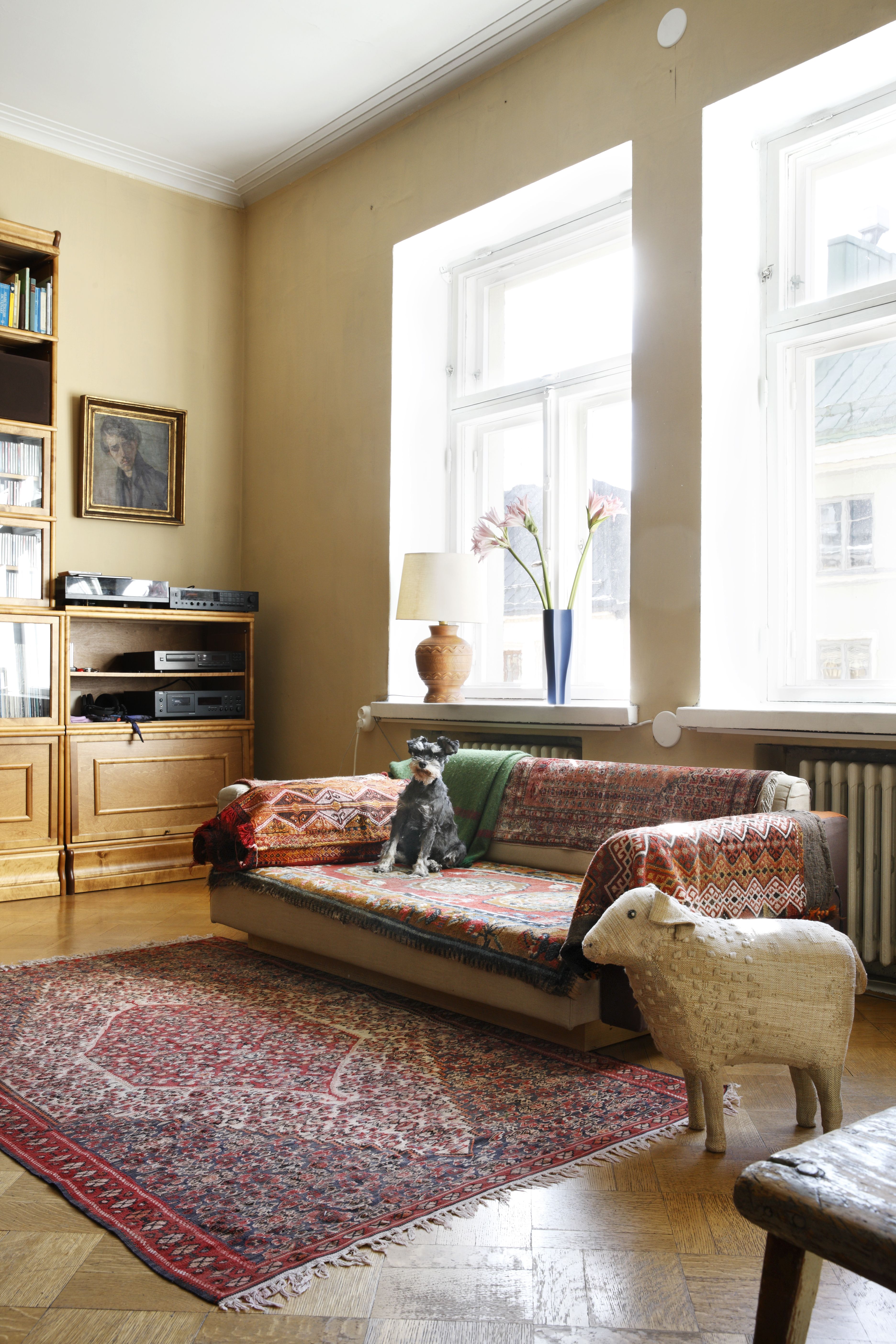 Perheen koira viihtyy Artekin sohvalla, joka on verhoiltu kirjavilla, vanhoilla matoilla. Kirjahylly on Billnäsin.