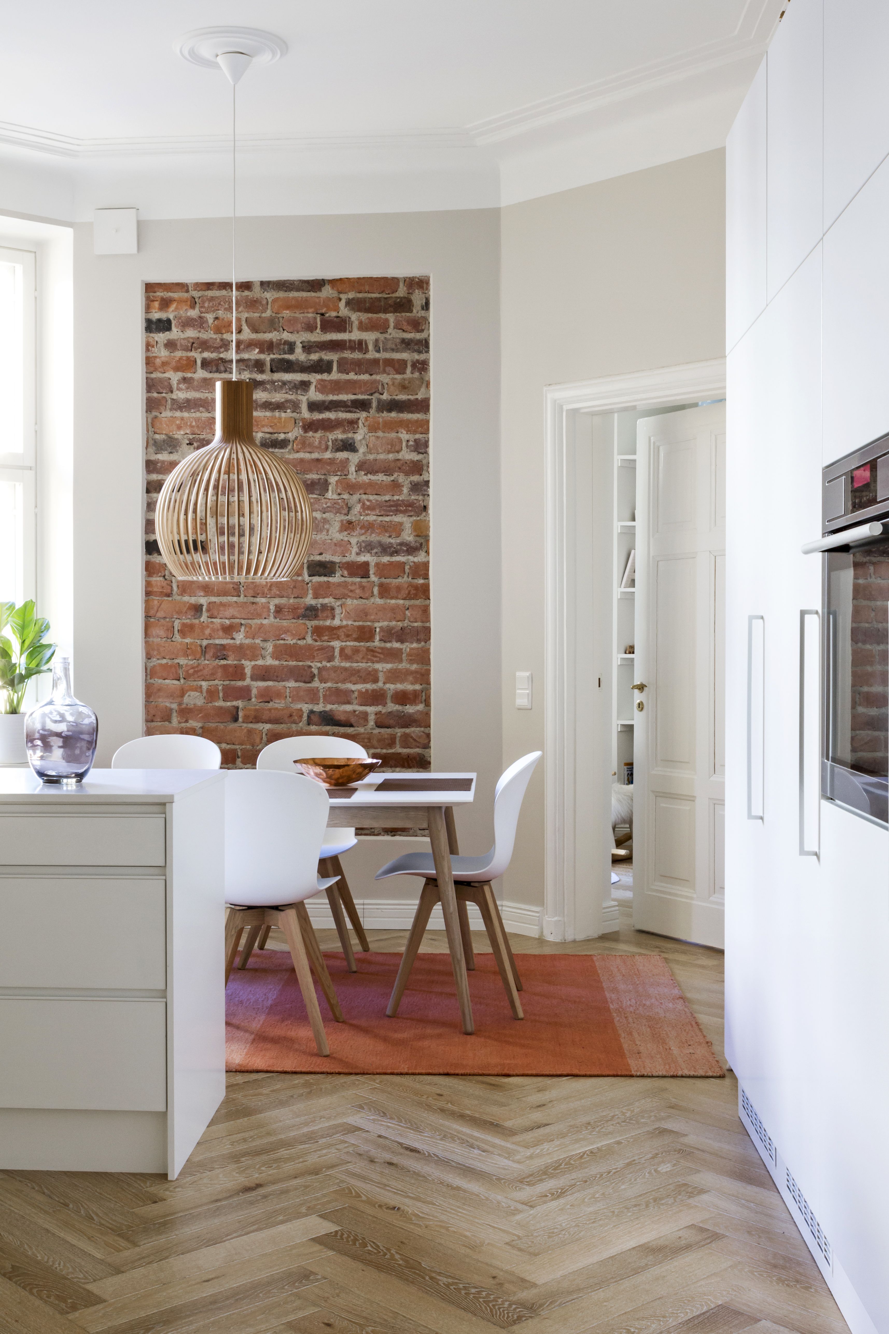 Keittiön ruokailutilan tiiliseinän yli satavuotiaissa tiilissä näkyvät valajien sormenjäljet. Alkuperäinen, kunnostettu peiliovi johtaa lastenhuoneeseen. Secto Designin Octo-valaisin on asukkaiden silmäterä. Muuton Varjo-matto sointuu tiiliseinän sävyihin. Matto on Formverkistä