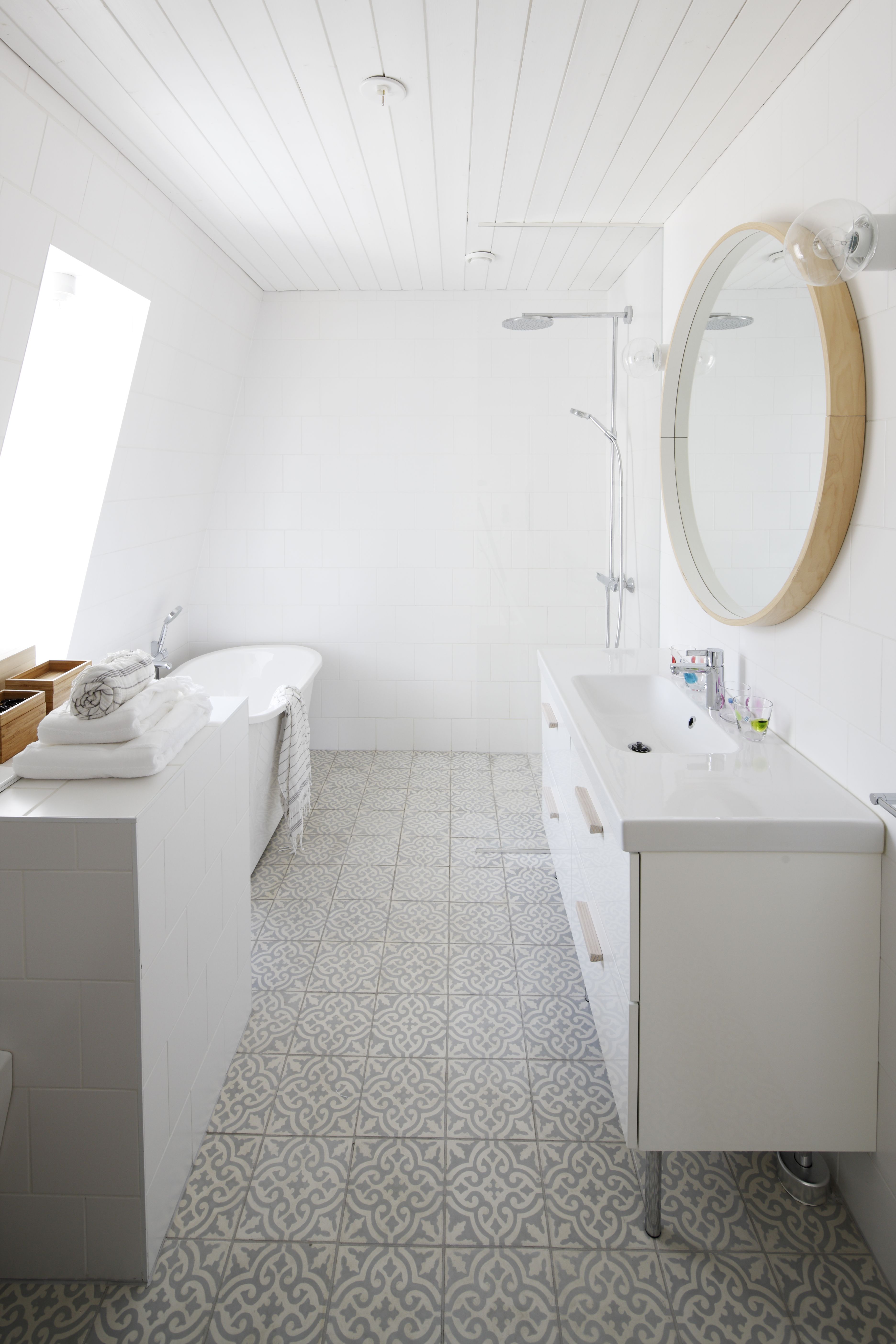 Yläkerran ikkunallisessa kylpyhuoneessa on lempeä väriskaala. Vino ikkuna ja sen viereen sijoitettu kylpyamme ovat arjen ylellisyyttä. Laatoitettu taso erottaa wc:n ja kylpytilan toisistaan ja kätkee sisälleen pyykkikuilun suoraan kodinhoitohuoneeseen.