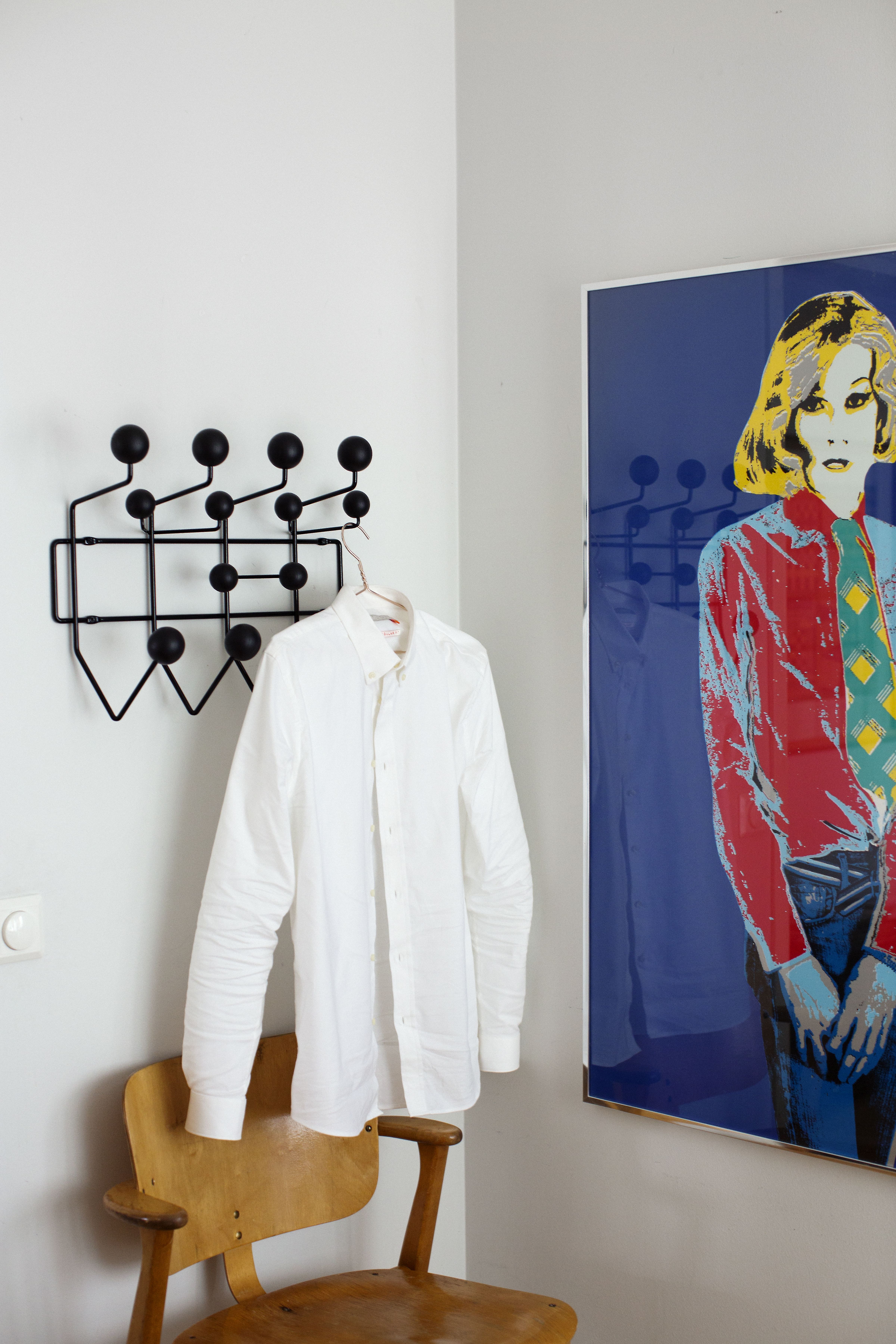 Ilmari Tapiovaaran Domus-tuoli pitää makuuhuoneessa seuraa Charles ja Ray Eamesin Vitralle suunnittelemalle Hang it all -naulakolle. Taulu on Kari Riipisen.