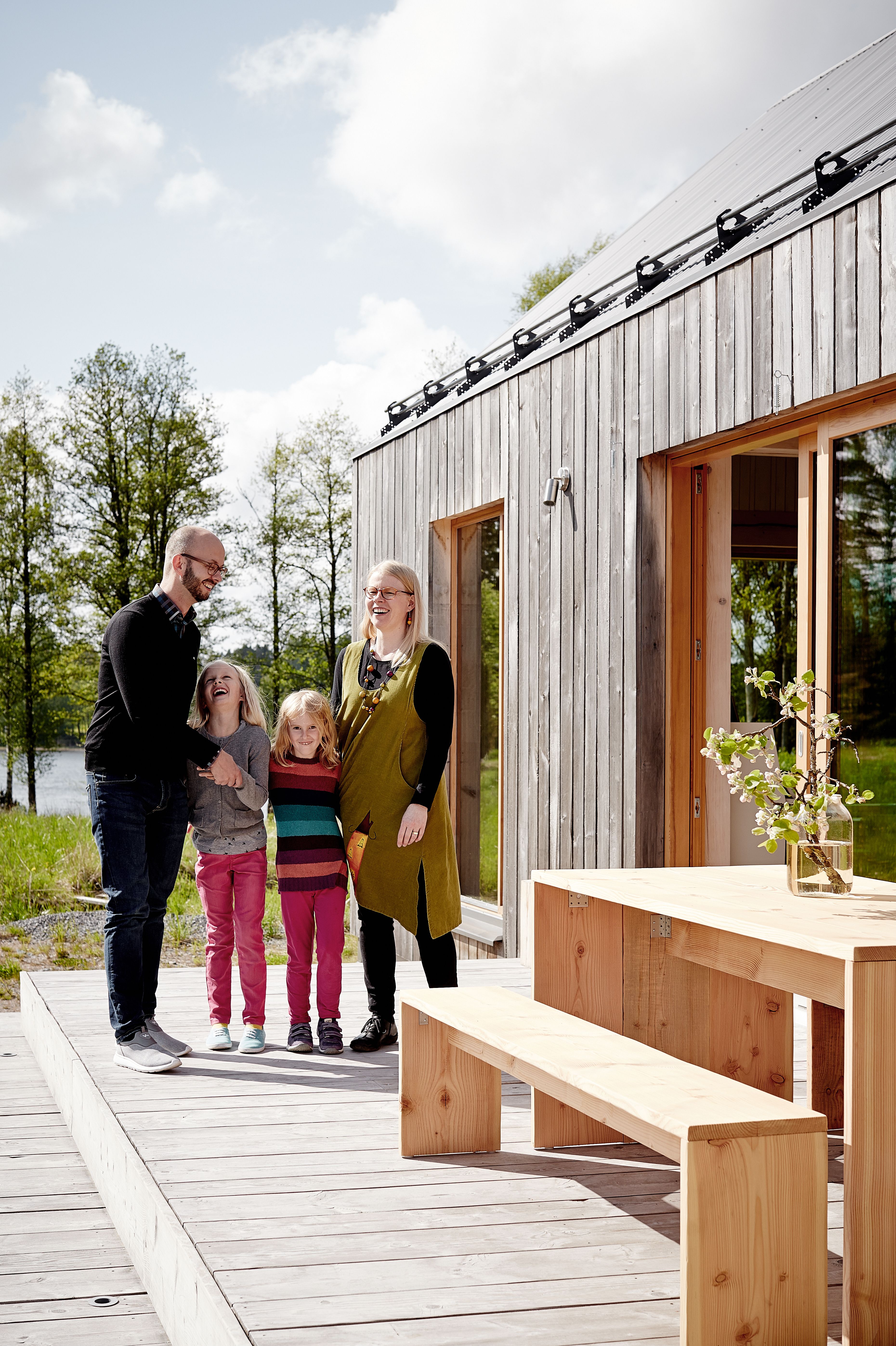 Sisäänkäynnin puolelle Mathias ja Sonja rakensivat terassin douglaskuusesta. Perheen takana siintää läheinen järvi.